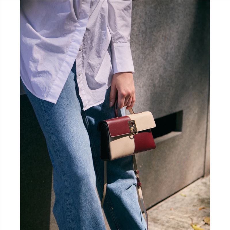 Stylish Chessboard Handbag - Fashionable cowhide leather bag with a chessboard pattern design, held by a person in casual attire.