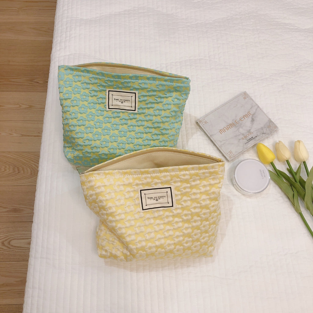 Fresh Solid Color Little Flower Women's Handbag
Two colorful, patterned women's cosmetic bags or pouches displayed on a white towel background, featuring a floral design and label.