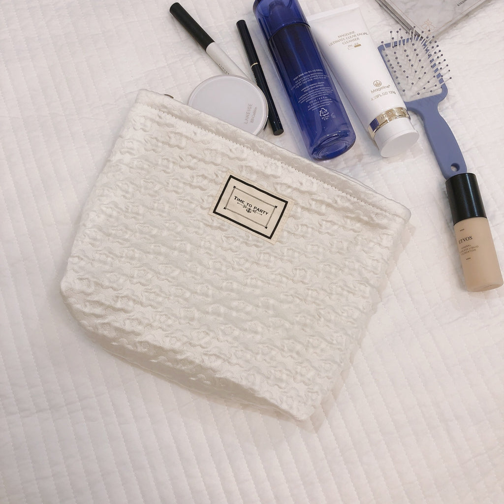 White textured makeup pouch with assorted beauty products